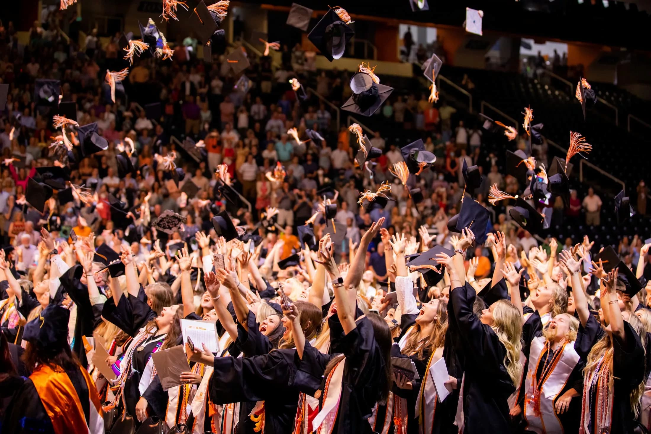 students throwing caps in air graduating